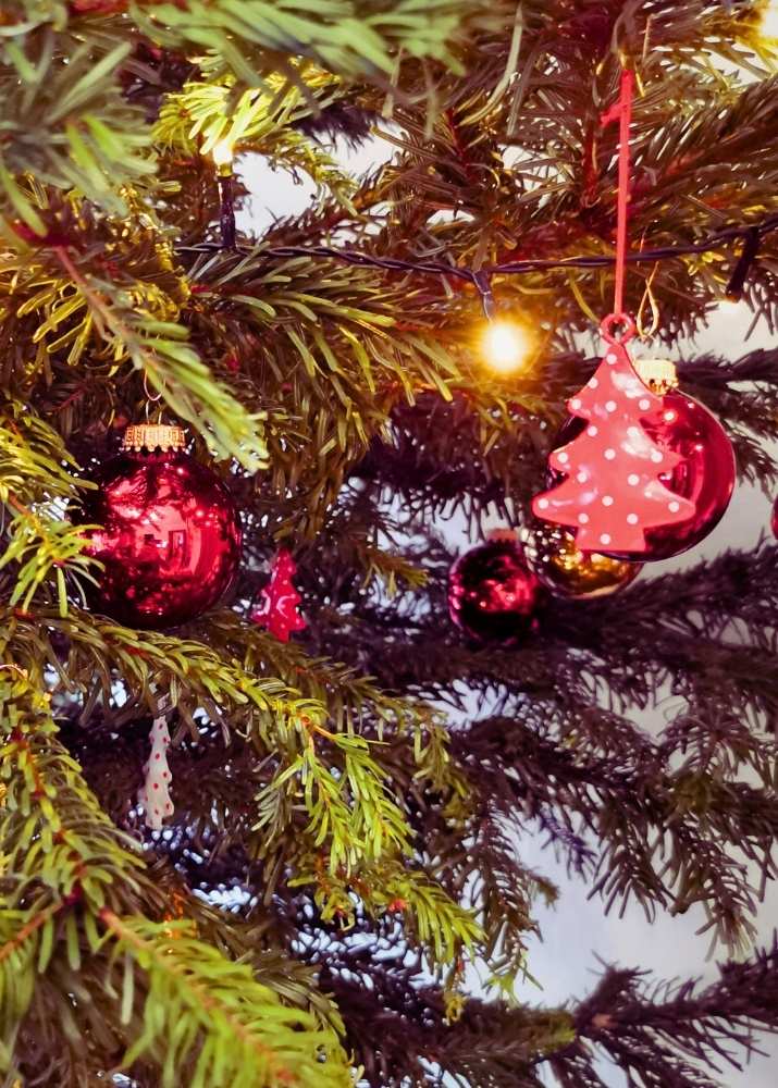 Kleinkind hängt Kugeln auf einen Christbaum