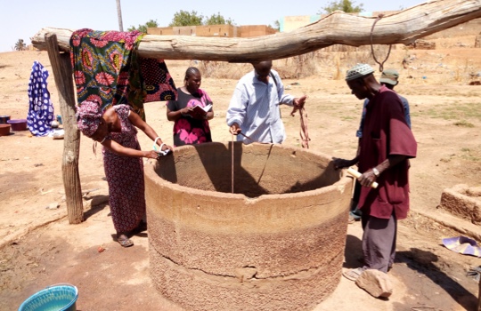 Vier Menschen stehen rund um einen Brunnen 